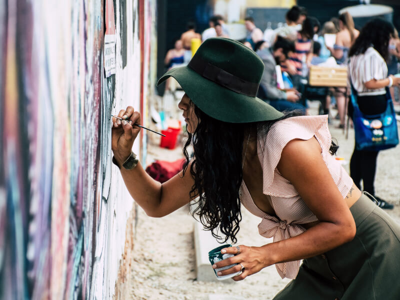 Woman wearing a hat painting on a wall